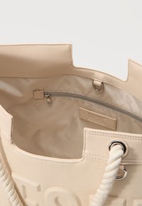 Μπεζ τσάντα tote Diesel με χειρολαβές από σκοινί, εσωτερική τσέπη με φερμουάρ, επένδυση με λογότυπο και ραμμένη ετικέτα Diesel στο εσωτερικό.