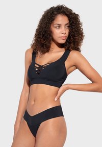 Čierny plavkový set s krížovým dizajnom na vrchu, širokými ramienkami a minimalistickými spodkami s hladkou textúrou.