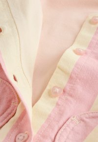 Pink and cream striped fabric with heart-shaped buttons. The texture is smooth, featuring a mix of solid and patterned areas.