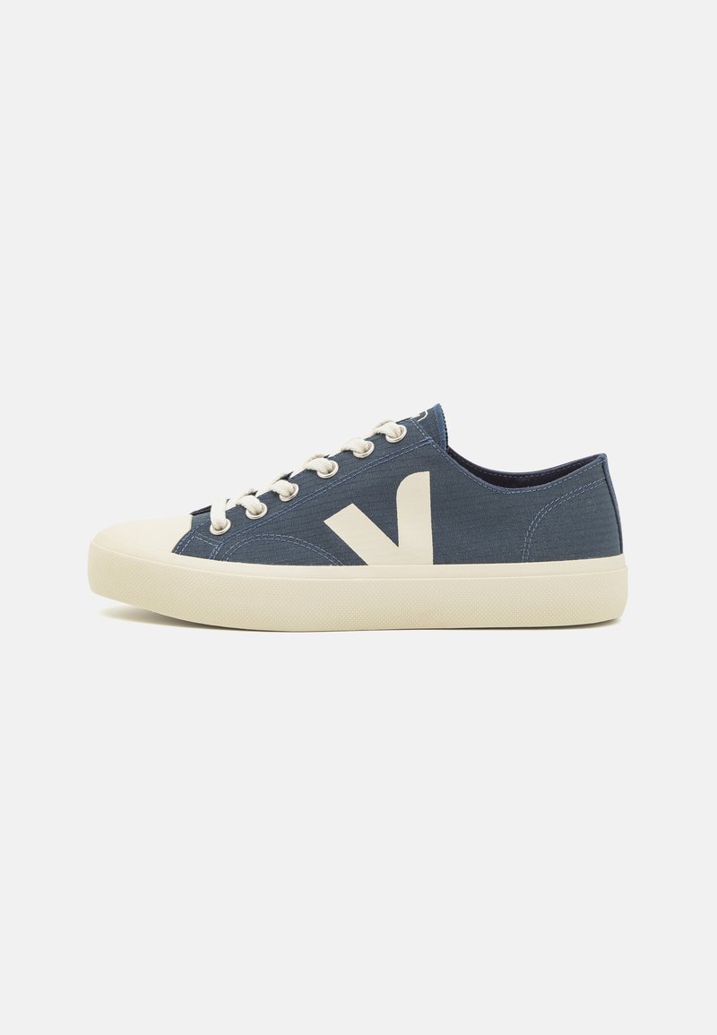 Blå kanvas sneakers med kremfarget gummisåle, med et fremtredende hvitt "V"-logo på siden og klassisk snøring.