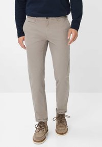 Light beige cotton pants with a straight cut, featuring front pockets, and a subtle texture. Paired with brown lace-up shoes.