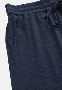 Marineblauwe joggers van textuurstof met een elastische tailleband en een trekkoord. Beschikt over zijzakken.