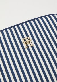 Torba typu tote z płótna w niebieskie i białe paski, z złotym monogramem. Krawędzie wykończone niebieską lamówką.