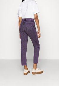 Liilanväriset, korkeavyötäröiset suorat farkut, joissa kaksi takataskua ja kohokuvioitu kangas. Yhdistetty valkoiseen t-paitaan ja neutraaleihin lenkkareihin.