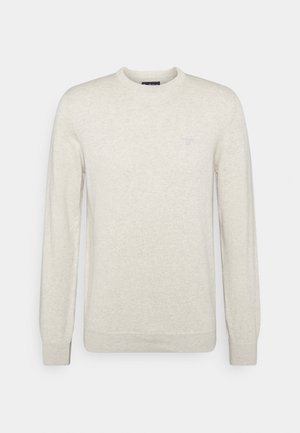 Pull beige clair à manches longues et col rond avec poignets et ourlet côtelés, orné d'un petit logo brodé sur la poitrine gauche.