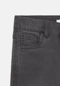 Mörkgrå denimjeans med platt midja, en liten framficka och standard sömnadsdetaljer. Materialet har en slät textur.