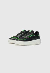 Zwarte sneakers met groene accenten, met een gladde leren bovenlaag, gaasdetails, ronde neus, dikke witte zool en veters. Merken op de zijkant.