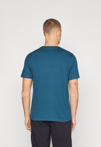 Türkises kurzärmeliges T-Shirt aus weichem Baumwollmaterial, mit Rundhalsausschnitt und normaler Passform, sichtbar genäht am Saum und an den Ärmeln.