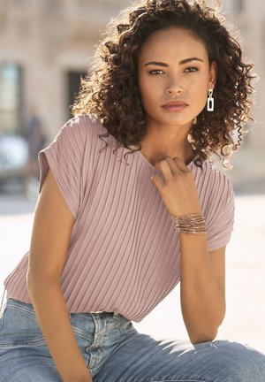 Short-sleeve, ribbed, mauve top paired with light blue denim, accessorized with a multi-strand metallic bracelet and drop earrings.
