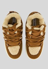 Sneaker in suede marrone con accenti in shearling sintetico crema, punta arrotondata, lacci robusti e dettagli testurizzati. Suola in gomma bianca visibile.