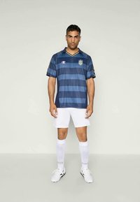 Camisa de futebol listrada em azul e marinho com decote em V, gola destacada, mangas pretas; combinada com calções brancos e meias até ao joelho.