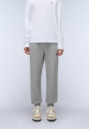 Grå sweatpants med en afslappet pasform, ribbede manchetter og et lille logo. Parret med en hvid polo t-shirt med lange ærmer og beige sneakers.