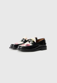 Loafers din piele patent neagră, cu un superior din material crem ce prezintă un model cu fructe; două benzi negre peste instep; toc mic.