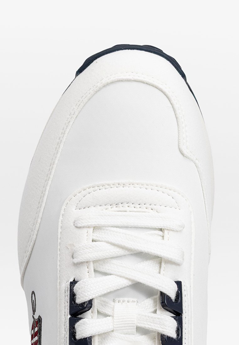 Sneaker bianca con una toma in tela liscia, accenti blu navy, punta rotonda e lacci bianchi piatti. Presenta un logo ricamato sul lato.