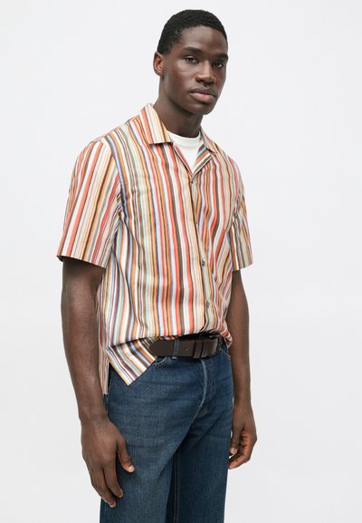 Korte mouwen overhemd met knopen en verticale meerkleurige strepen, gemaakt van licht materiaal. Gecombineerd met donkerblauwe spijkerbroek en een bruine riem.