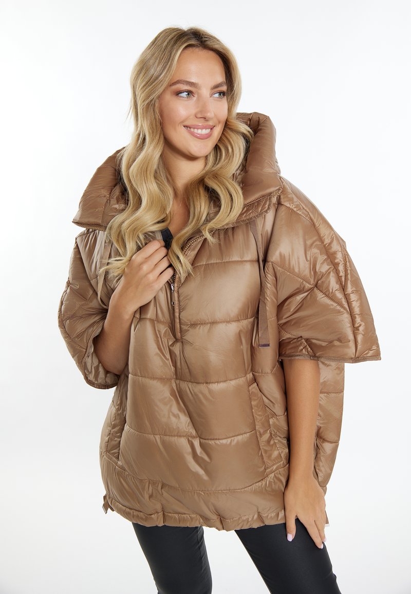 Puffjacke in einem hellbraunen Farbton mit hohem Kragen, halbem Reißverschluss vorne und oversize Schnitt. Verfügt über eine gesteppten Textur und elastischen Saum.