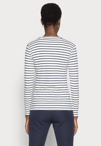 Långärmad tröja med horisontella marinblå och vita ränder, mjukt bomullsmaterial, rund halsringning och en figurnära silhuett.