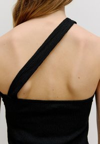 Zwarte geribbelde tanktop met een brede, gestructureerde schouderband en een open rugontwerp van een zachte, rekbare stof.