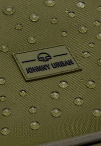 Tessuto verde oliva resistente all'acqua con una texture di gocce in rilievo. Il logo "JOHNNY URBAN" è impresso in nero su una toppa rettangolare.