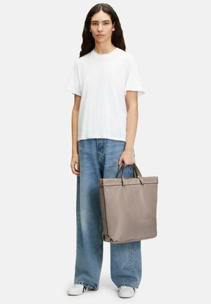 Grau Tote-Bag mit doppelten Griffen, aus strukturiertem Material. Kombiniert mit einem weißen T-Shirt und lockeren blauen Jeans, leger getragen.