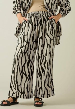 Schwarz-weiße, in Zebra-Optik gestaltete weit geschnittene Hosen mit elastischem Bund und seitlichen Taschen, aus leichtem Stoff.