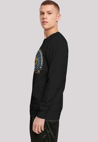 Sort sweatshirt med rund halsudskæring og lange ærmer, med et farverigt trykt grafisk motiv på fronten. Glat tekstur med ribbede manchetter.