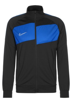 Czarna i niebieska sportowa kurtka Nike na zamek błyskawiczny z wysokim kołnierzem i długimi rękawami, z białym logo Nike na niebieskim panelu na piersi.