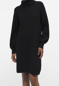 Schwarzes Strickkleid mit Stehkragen, langen Puffärmel, geripptem Muster und seitlichen Schlitzen. Es verfügt über eine lockere Passform und ein knielanges Design.