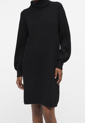 Abito nero lavorato a maglia con collo alto, maniche lunghe a sbuffo, texture a coste e spacchi laterali. Caratterizzato da una vestibilità comoda e un design al ginocchio.