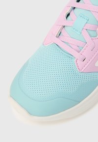 Zapatilla deportiva azul claro con parte superior de malla, detalles en rosa y superposiciones texturizadas. Cuenta con cordones planos y suela acolchada.