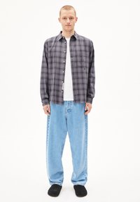 Grijze en zwarte geruite overhemden met lange mouwen, gecombineerd met losse lichtblauwe denim jeans en zwarte schoenen. Eenvoudig ontwerp en zachte stoftextuur.