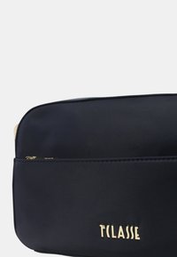 Borsa in nylon blu navy con hardware dorato, dotata di una tasca frontale con zip, design rettangolare elegante e nome del marchio mostrato in modo evidente in oro.