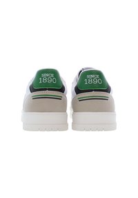 Sneaker bianche con dettagli in suede grigio, linguette verdi sul tallone con la scritta "SINCE 1890" in bianco, suola in gomma con trazione. Vista posteriore.