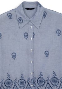 Hellblau und weiß gestreifte Knopfhemd mit blauer floraler Stickerei, die verstreut und entlang dem unteren Saum verläuft.