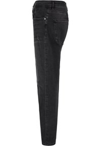 Musta farkut slim fit -leikkauksella, joissa on keskitason vyötärö, takataskut ja kuluneet yksityiskohdat vasemmassa reidessä. Sileä pinta.