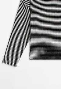 Maglia a maniche lunghe a righe bianche e nere con scollatura a girocollo. Tessuto a maglia e vestibilità leggermente rilassata. Nessun hardware o dettaglio visibile.