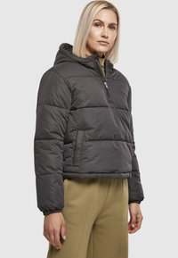 Kort, hætteklædt dunjakke i mørkegrå polyester med lynlås foran og sidelommer, med elastiske manchetter for en tæt pasform.