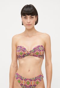 Bikini-set met een strapless top met een twisted detail, versierd met een kleurrijk bloemen- en geometrisch patroon op een paarse achtergrond.