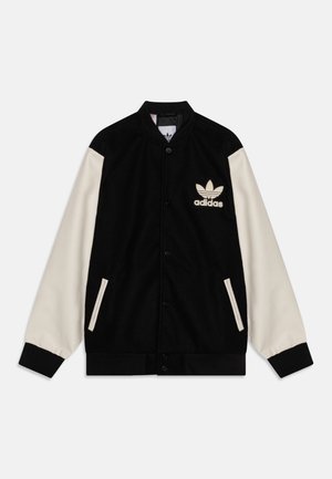 Veste varsity Adidas noire et crème avec fermeture à boutons, deux poches avant, poignets côtelés et logo Adidas sur la poitrine gauche.