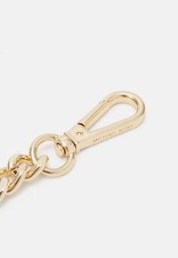 Gold metal keychain with a lobster clasp, detailed hardware, and smooth, polished finish. Features an engraved "MICHAEL KORS" logo.