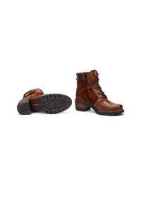 Brown leather ankle boots with lace-up front, side zipper closure, textured rubber sole, and stacked heel. Features contrast stitching and accents.