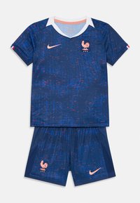 Kék Nike fociszerel, amely texturált kialakítással, fehér gallérral és narancs színű részletekkel rendelkezik. Rövidujjú felsőt és címeres szárt tartalmaz.