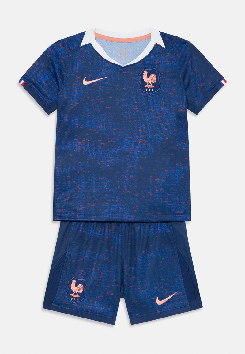 Kék Nike fociszerel, amely texturált kialakítással, fehér gallérral és narancs színű részletekkel rendelkezik. Rövidujjú felsőt és címeres szárt tartalmaz.