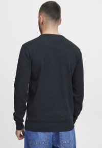 Mörkgrå tröja för män med långa ärmar, rund halsringning, ribbade muddar och nederkant, tillverkad av ett mjukt texturerat tyg.