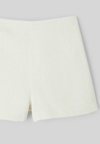Shorts blancs texturés avec un motif à carreaux subtil, présentant un ourlet droit et sans fermetures ni ornements visibles.