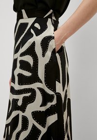 Zwart-witte rok met gedurfde abstracte patronen, een aansluitende tailleband en zijkousen. Gladde stof met contrasterende textuurdetails.