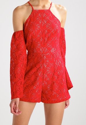 Combinaison rouge en dentelle avec des motifs floraux complexes, décolleté halter et manches longues à épaules dénudées. Présente un corsage ajusté et un short.