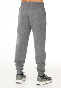 Grå sweatpants med en strukturerad tygkvalitet, elastisk midja och nedtrappade muddar. Bärs med grå och svarta träningsskor.