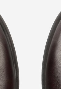 Bruine leren schoenen met een gladde textuur, ronde neus en geen zichtbare veters, met een lichte glans en een stevige zwarte zool.