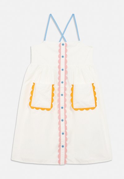 Biele šaty bez rukávov s modrými krížovými ramienkami na chrbte, predné gombíky lemované ružovými vlnkami a dve predné vrecká s oranžovými vlnkovanými okrajmi.
